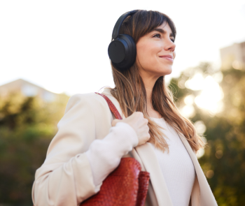 Woman holding purse with noise cancelling headphones over ear